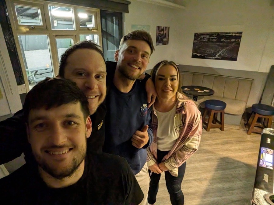 Four Evolve players smiling for a group selfie in the bar between frames at a local Andover venue