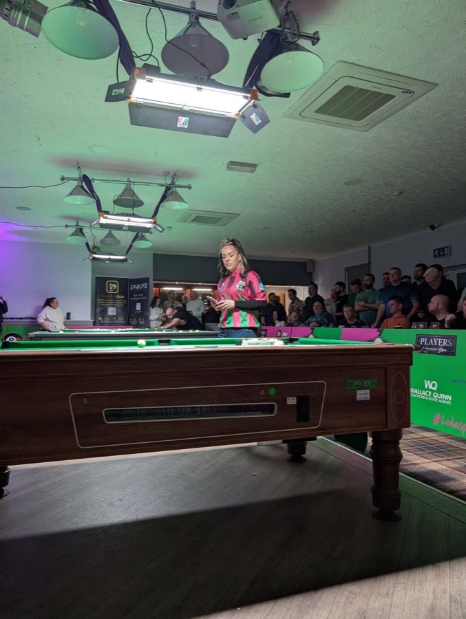 Player at the table under the match lights in front of a packed crowd at an Evolve night at the Wolversdene Club, Andover